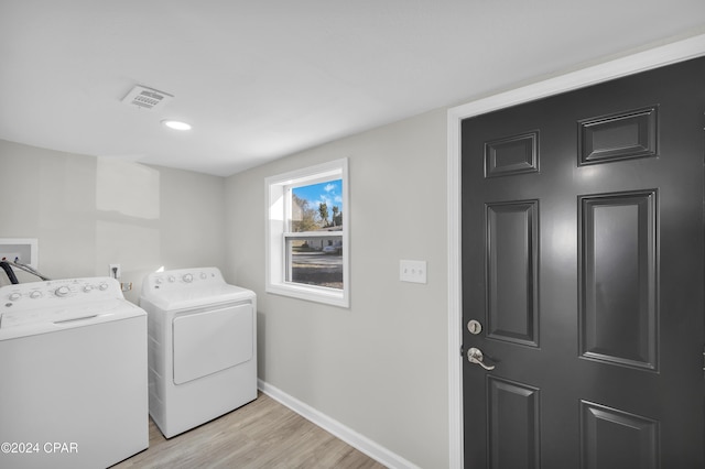 clothes washing area featuring washing machine and clothes dryer, visible vents, light wood finished floors, baseboards, and laundry area