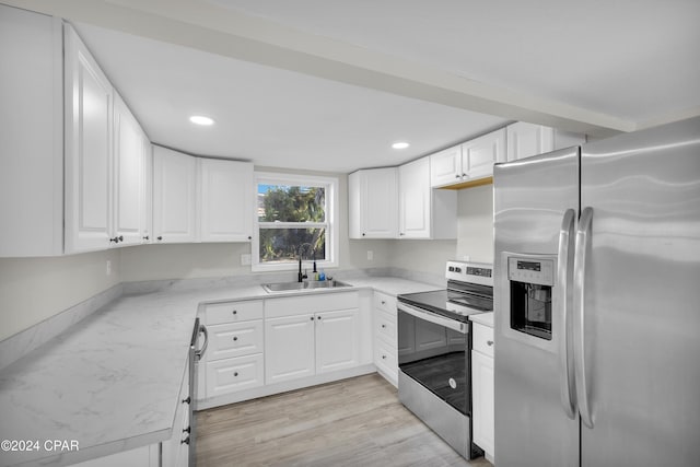 kitchen with white cabinetry, sink, stainless steel appliances, and light hardwood / wood-style flooring