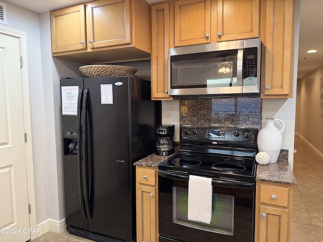 kitchen with black appliances, light tile patterned flooring, and dark stone counters