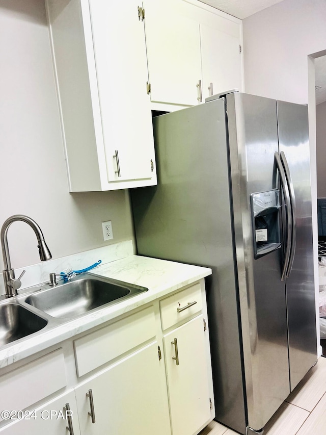 kitchen with white cabinetry, sink, and stainless steel fridge