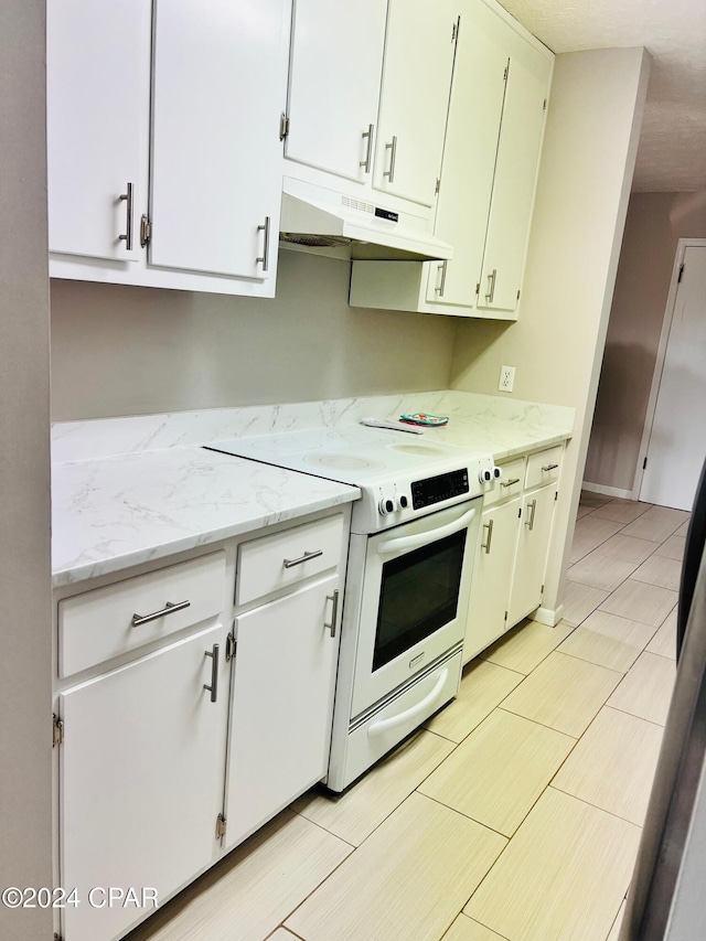 kitchen with white cabinetry, light stone countertops, light tile patterned floors, and white electric stove