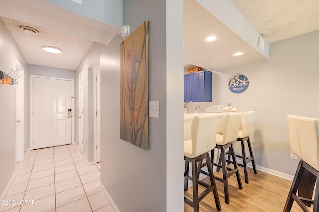 corridor featuring light tile patterned floors and a textured ceiling