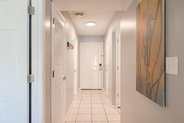 corridor featuring light tile patterned floors and a textured ceiling