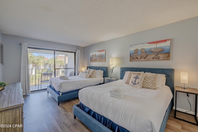 bedroom with hardwood / wood-style flooring, access to exterior, and a textured ceiling