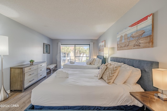 bedroom with light hardwood / wood-style floors and a textured ceiling