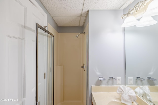 bathroom with a paneled ceiling, a shower, and vanity