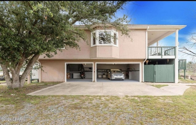 rear view of property featuring a balcony, a garage, and a lawn