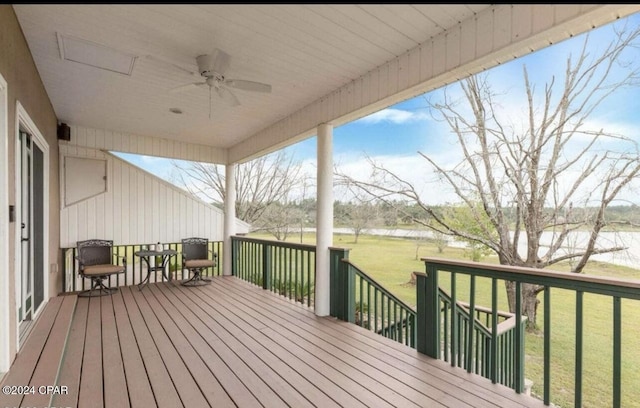 wooden terrace featuring a water view, ceiling fan, and a lawn