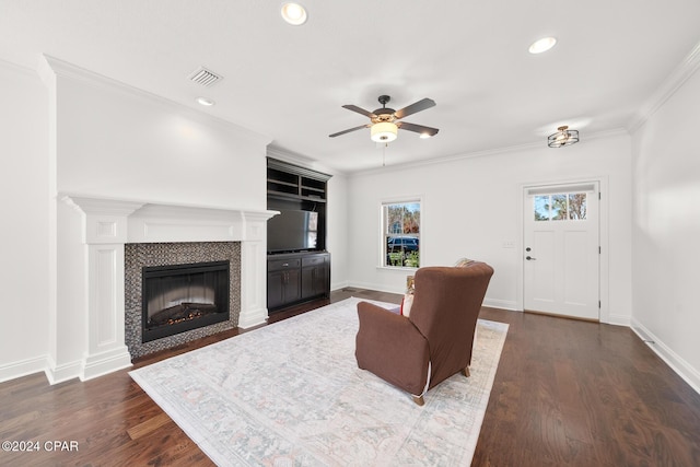 living room with dark hardwood / wood-style flooring, crown molding, a fireplace, and ceiling fan