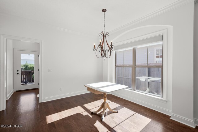 unfurnished dining area with a notable chandelier, dark hardwood / wood-style flooring, and crown molding