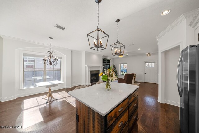 kitchen with pendant lighting, dark wood-type flooring, stainless steel fridge, ornamental molding, and a kitchen island