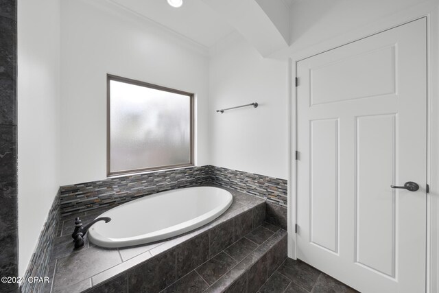 bathroom with crown molding and tiled bath