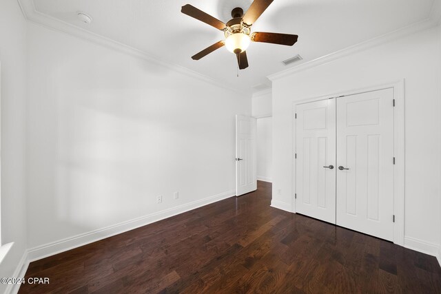 unfurnished bedroom with a closet, dark hardwood / wood-style flooring, ceiling fan, and crown molding