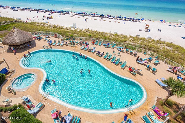 view of pool featuring a view of the beach, a water view, and a community hot tub