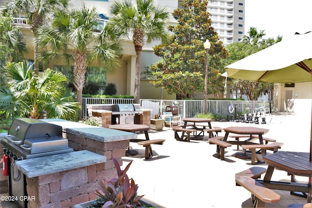 view of patio / terrace featuring exterior kitchen, outdoor dining area, fence, and grilling area