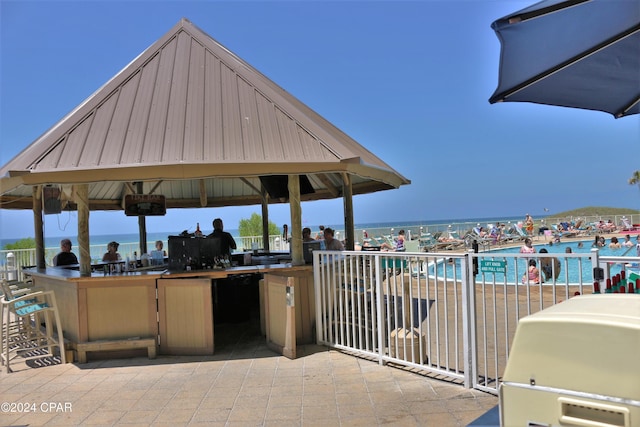 view of patio / terrace featuring a water view, outdoor dry bar, and a gazebo