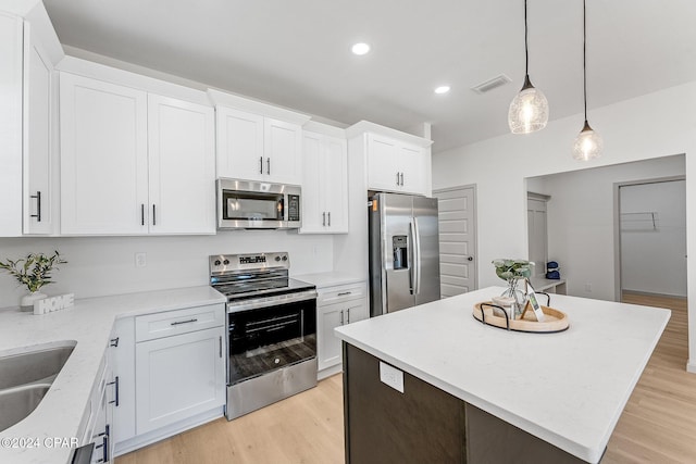 kitchen featuring light wood finished floors, visible vents, a center island, appliances with stainless steel finishes, and white cabinetry