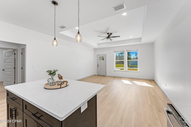 kitchen with ceiling fan, a tray ceiling, visible vents, and light wood-style flooring