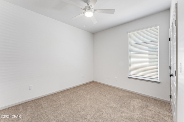 carpeted spare room featuring baseboards and ceiling fan