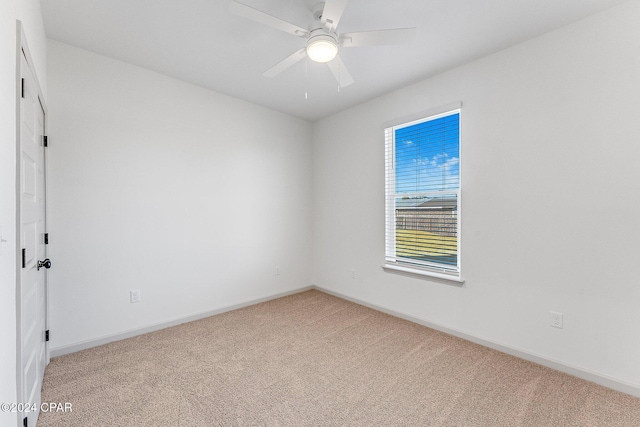 spare room featuring baseboards, light carpet, and a ceiling fan