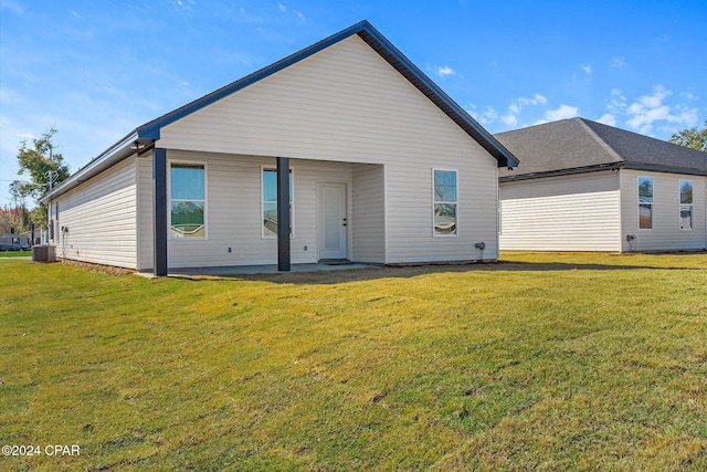 back of property featuring central air condition unit and a yard