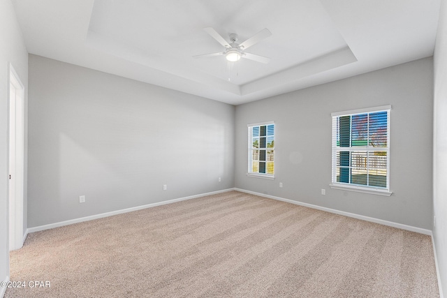 spare room with baseboards, carpet flooring, a ceiling fan, and a tray ceiling