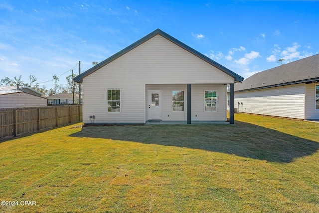 rear view of house with a lawn and fence