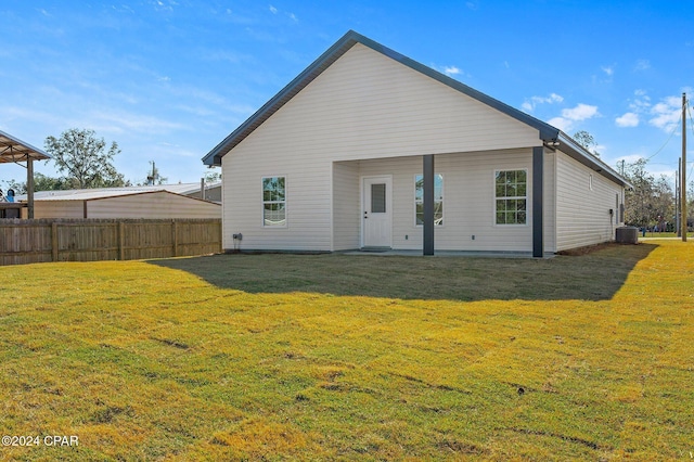 rear view of property with central air condition unit, a yard, and fence