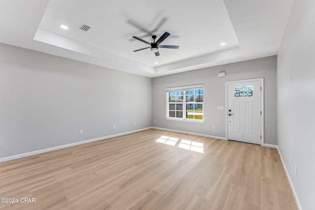 entrance foyer with light wood-type flooring, a tray ceiling, baseboards, and ceiling fan