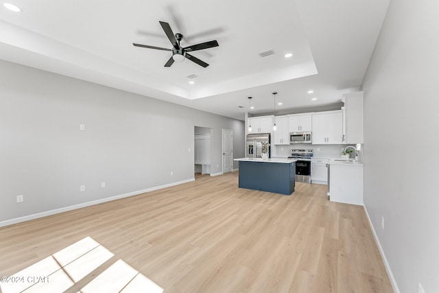 kitchen featuring a center island, open floor plan, light countertops, appliances with stainless steel finishes, and a ceiling fan