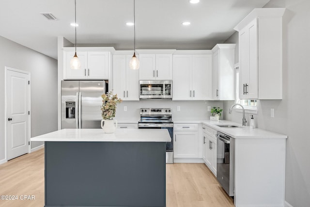 kitchen with white cabinets, light wood-type flooring, appliances with stainless steel finishes, and a sink