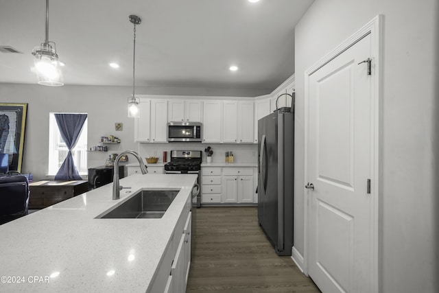 kitchen featuring light stone countertops, appliances with stainless steel finishes, decorative light fixtures, and white cabinets