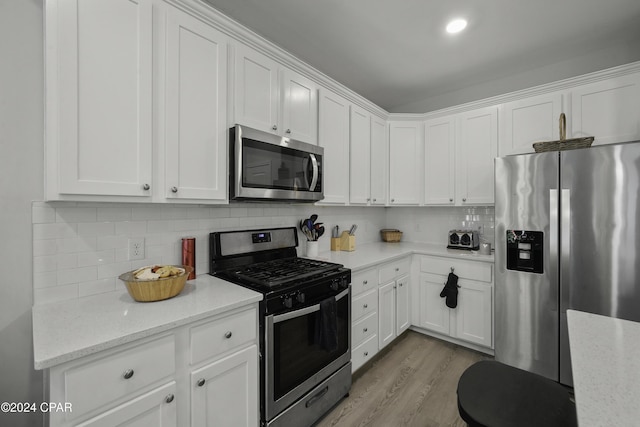 kitchen featuring white cabinets, appliances with stainless steel finishes, and light stone countertops