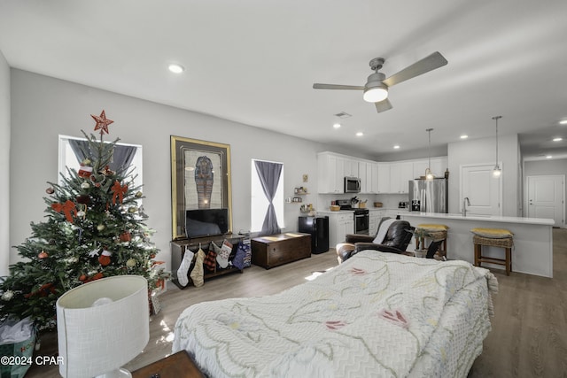 bedroom featuring ceiling fan, stainless steel fridge, light hardwood / wood-style floors, and sink