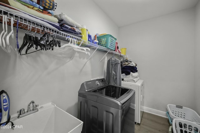 laundry area featuring washer and dryer, dark wood-type flooring, and sink