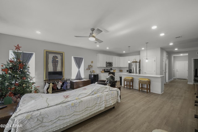 bedroom with stainless steel fridge, ceiling fan, and light hardwood / wood-style floors