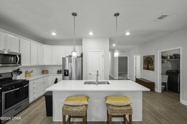 kitchen featuring white cabinets, appliances with stainless steel finishes, sink, and an island with sink