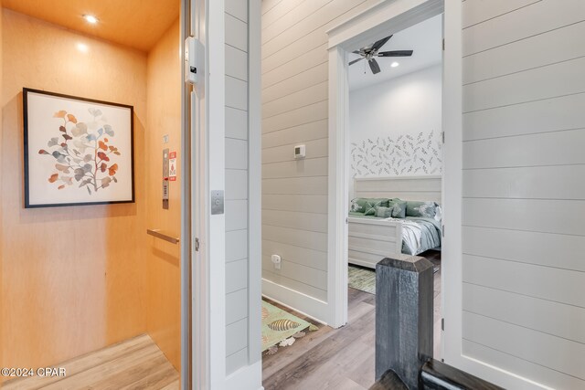 bathroom featuring hardwood / wood-style floors, ceiling fan, and wooden walls