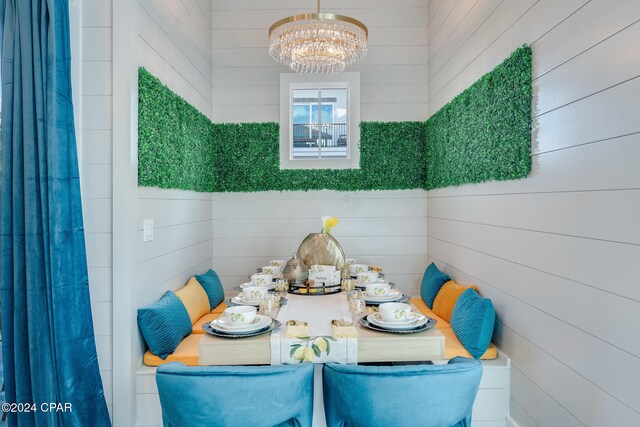 dining area with wood walls and a chandelier