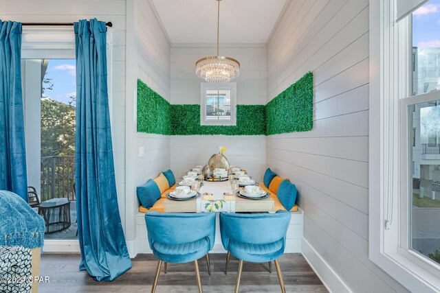 dining space featuring wood-type flooring, a healthy amount of sunlight, and an inviting chandelier