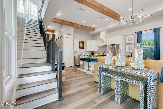 dining room with a chandelier, beamed ceiling, and light hardwood / wood-style floors