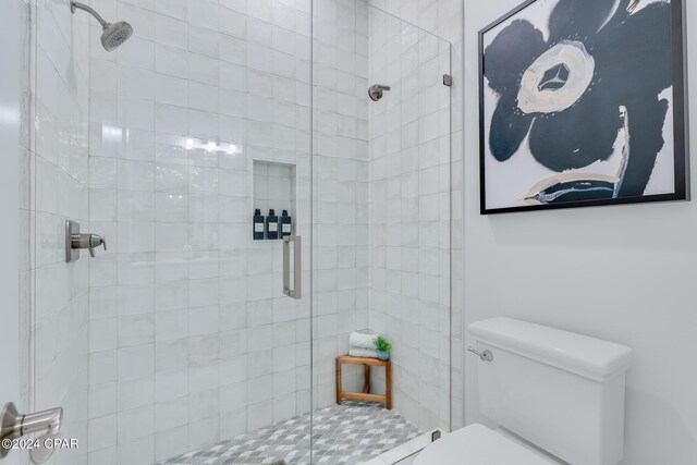 bathroom featuring a shower with shower door and toilet