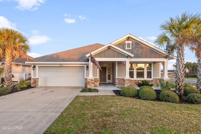 view of front of house featuring covered porch, a garage, and a front yard