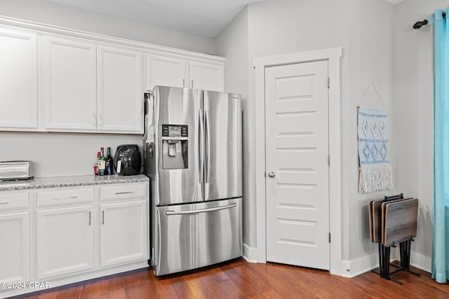 kitchen with white cabinets, dark hardwood / wood-style floors, stainless steel fridge, and light stone counters