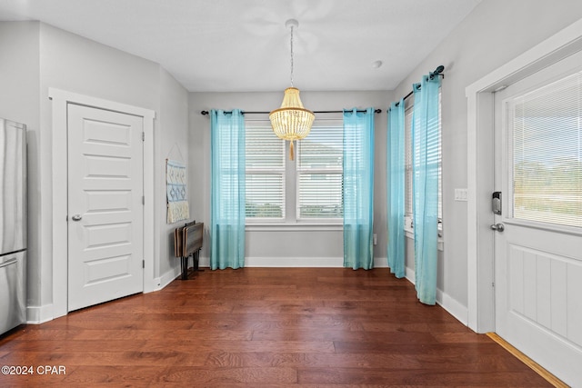 unfurnished dining area featuring dark wood-type flooring and a notable chandelier