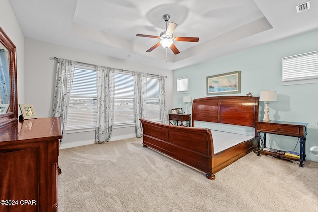 bedroom with a tray ceiling, ceiling fan, and light colored carpet