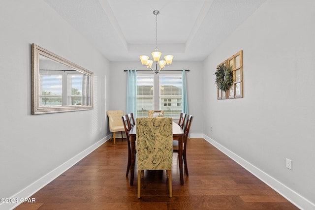 dining space featuring a tray ceiling, an inviting chandelier, and dark hardwood / wood-style floors