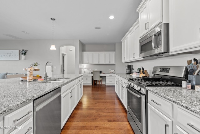 kitchen with appliances with stainless steel finishes, dark hardwood / wood-style flooring, sink, white cabinets, and hanging light fixtures