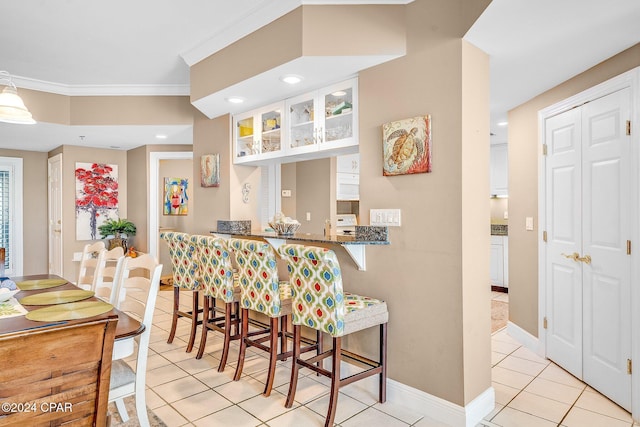 bar with white cabinets, light tile patterned floors, crown molding, and dark stone counters