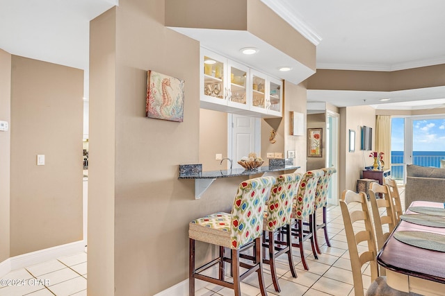 kitchen with white cabinets, light tile patterned flooring, a water view, and kitchen peninsula